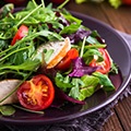 Een zwart bord met een salade met sla, tomaat, komkommer Een zwart bord met een salade met sla, tomaat, komkommer