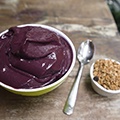 Een schaaltje met acai bessen yoghurt, granen en een lepel Een schaaltje met acai bessen yoghurt, granen en een lepel