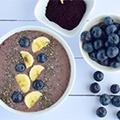 Een witte tafel met daarop een schaaltje met acai bessen, besen poeder en een kom met acai pap Een witte tafel met daarop een schaaltje met acai bessen, besen poeder en een kom met acai pap