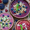 Een tafel met 3 schaaltjes acai bessen yoghurt versiert met wat bessen, frambozen en granen Een tafel met 3 schaaltjes acai bessen yoghurt versiert met wat bessen, frambozen en granen