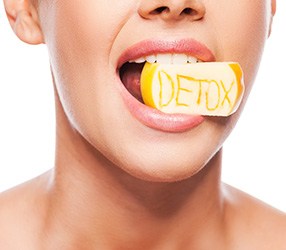 Mond van een vrouw met daarin een geel stuk zeep waar detox in staat gekrast