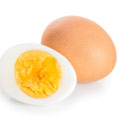 Een gekookt ei wat is gepelt en door de helft is gesneden met daarnaast een ander ongepelt ei 