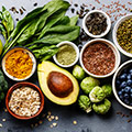 Een tafel met allerlei gezonde voedingsmiddelen zoals advocado, bessen, sla en kruiden
