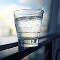 Glas water met daarin ijsklontjes voor een zwart raam