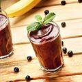 Een tafel met daarop 2 glazen met acai bessen smoothie en wat losse bessen op de tafel Een tafel met daarop 2 glazen met acai bessen smoothie en wat losse bessen op de tafel