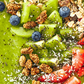 Groen pap met daarin kiwi, aardbeien, granen en blauwe bessen