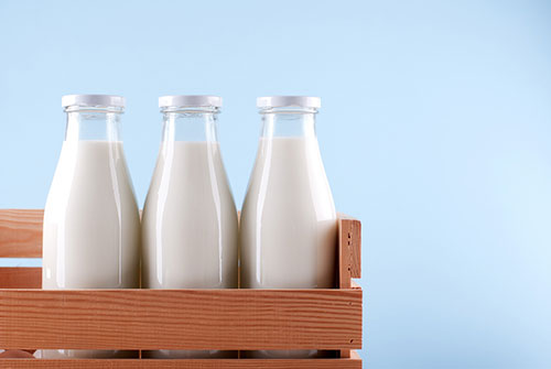 Een houte kistje met daarin drie gesloten flessen melk Een houte kistje met daarin drie gesloten flessen melk