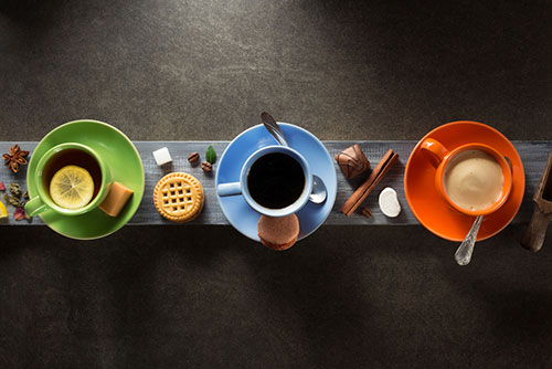 Groene kopje met thee, blauw kopje met koffie en oranje kopje met koffie Groene kopje met thee, blauw kopje met koffie en oranje kopje met koffie
