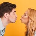Een man en vrouw die elkaar een kus willen geven met een oranje achtergrond
