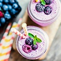 Paarse smoothie versiert met bramen, munt en een rietje Paarse smoothie versiert met bramen, munt en een rietje