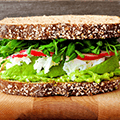 Zijkant van een sandwich met bruin brood en groente ertussen