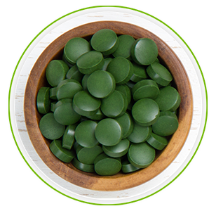Houte schaaltje met daarin chlorella tabletten van bovenaanzicht Houte schaaltje met daarin chlorella tabletten van bovenaanzicht