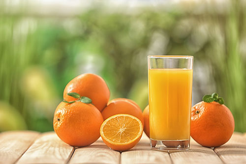 Tafel met daarop meerdere sinaasappels en een glas sinaasappelsap Tafel met daarop meerdere sinaasappels en een glas sinaasappelsap