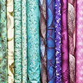 Stapel van opgevouwen lappen stof in de kleuren groen, lichtblauw, paars en roze Stapel van opgevouwen lappen stof in de kleuren groen, lichtblauw, paars en roze