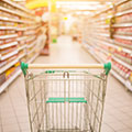 Een leeg gangpad van een supermarkt met in het midden een lege winkelwagen